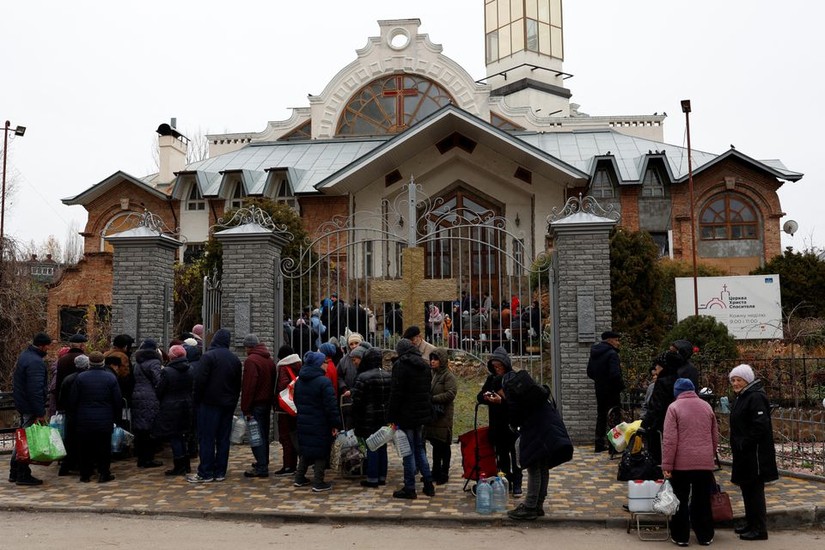 Người dân Kherson xếp hàng nhận hỗ trợ thực phẩm và nước bên ngoài một nhà thờ ngày 22/11. Ảnh: Reuters