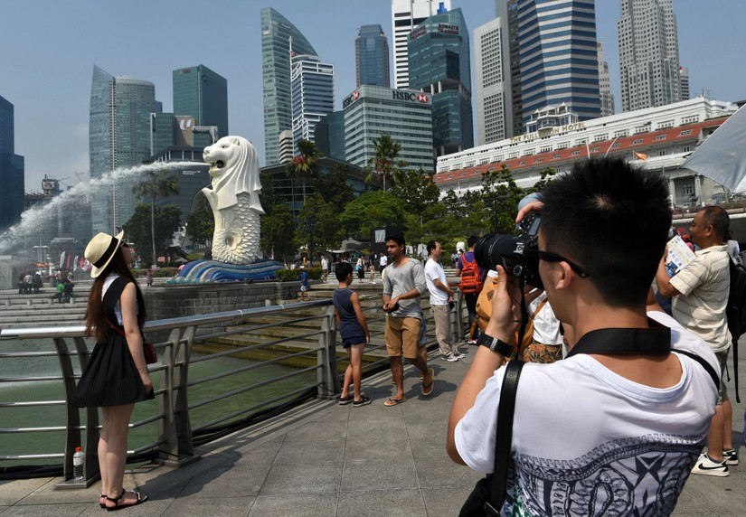 Du khách Trung Quốc chụp ảnh với tượng Merlion ở Singapore. Ảnh: AFP