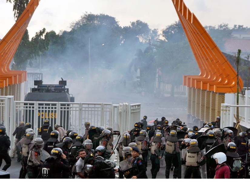 Người hâm mộ bóng đá và cảnh sát đụng độ bên ngoài sân vận động Jatidiri, Indonesia ngày 17/2. Ảnh: AP