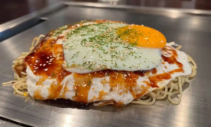 Okonomiyaki là món đặc sản của Hiroshima với sự kết hợp của các nguyên liệu gồm bột bánh, trứng, mì yakisoba, thịt và bắp cải ăn kèm sốt và rong biển. Ảnh: Guardian