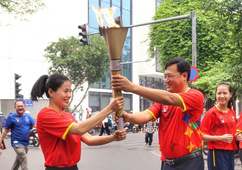 Đuốc được truyền tay đến vận động viên điền kinh Nguyễn Thị Huyền để cùng các vận động viên rước quanh hồ Hoàn Kiếm. Ảnh: TTXVN