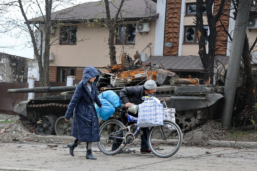 Người dân địa phương đi ngang qua một chiếc xe tăng bị phá hủy trong trận giao tranh ác liệt ở Mariupol, Ukraine, ngày 19/4. ảnh: AP