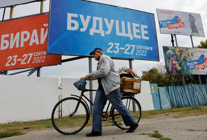 Một người dân đi qua biển hiệu kêu gọi bỏ phiếu trưng cầu dân ý ở Zaporizhzhia, ngày 26/9. Ảnh: Reuters