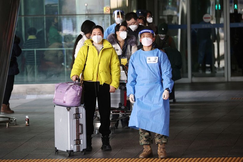 Một quân nhân Hàn Quốc mặc đồ bảo hộ cá nhân (PPE) dẫn một nhóm du khách Trung Quốc đến trung tâm xét nghiệm Covid-19 ở Sân bay Quốc tế Incheon, ngày 4/1. Ảnh: Reuters
