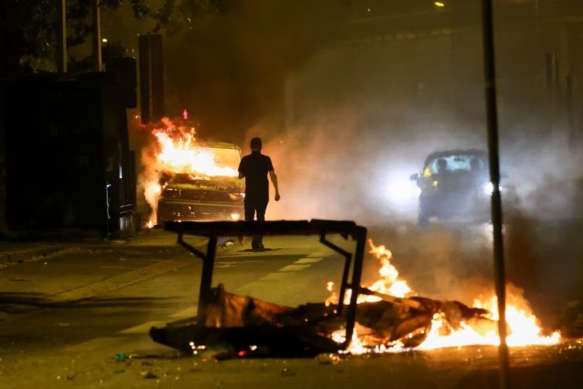 Một người đi gần những phương tiện bốc cháy trên đường phố Nanterre, ngoại ô Paris, Pháp, ngày 1/7. Ảnh: Reuters
