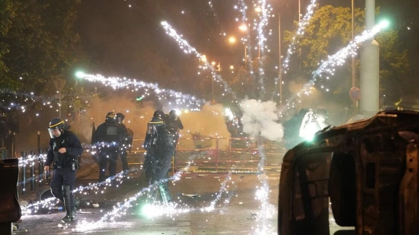 Pháo hoa nổ gần các cảnh sát chống bạo động Pháp trong cuộc biểu tình ở Nanterre, Paris, ngày 28/6. Ảnh: AFP