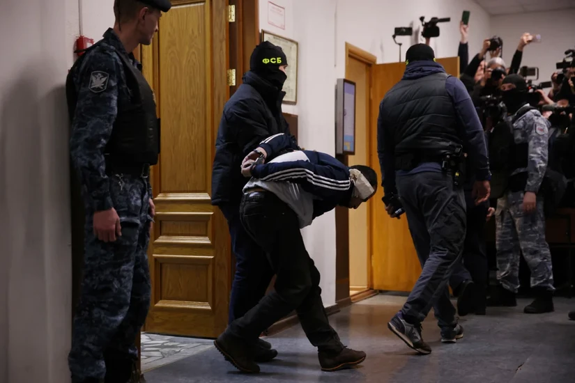 Cảnh sát Nga áp giải nghi phạm vụ tấn công khủng bố vào phòng kính. Ảnh: Reuters