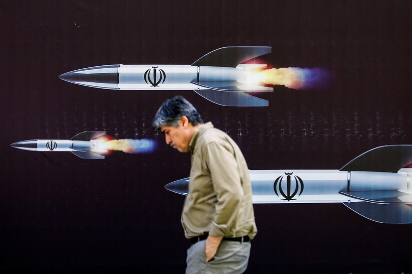 Một người đàn ông đi ngang qua biểu ngữ về tên lửa tại một con phố ở Tehran, Iran, ngày 19/4. Ảnh: Times of Israel 