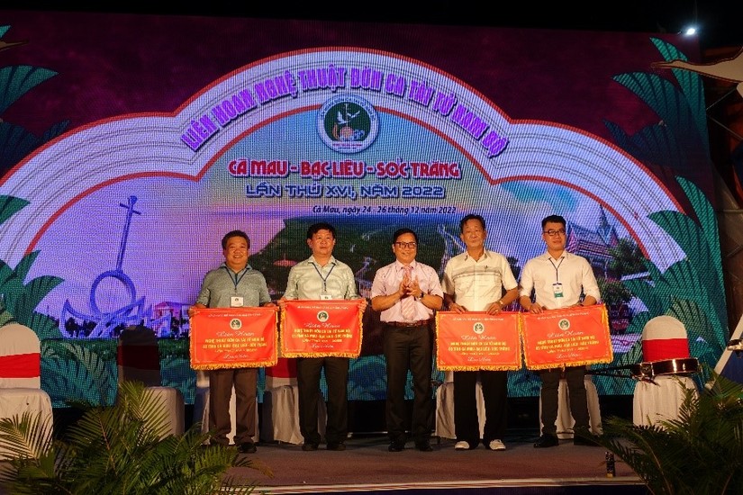 Phó Giám đốc Sở Văn hóa, Thể thao và Du lịch tỉnh Cà Mau Tạ Hoàng Hiện (đứng giữa) trao cờ thi đua cho các đơn vị tham gia Liên hoan. Ảnh: CTTĐT tỉnh Cà Mau